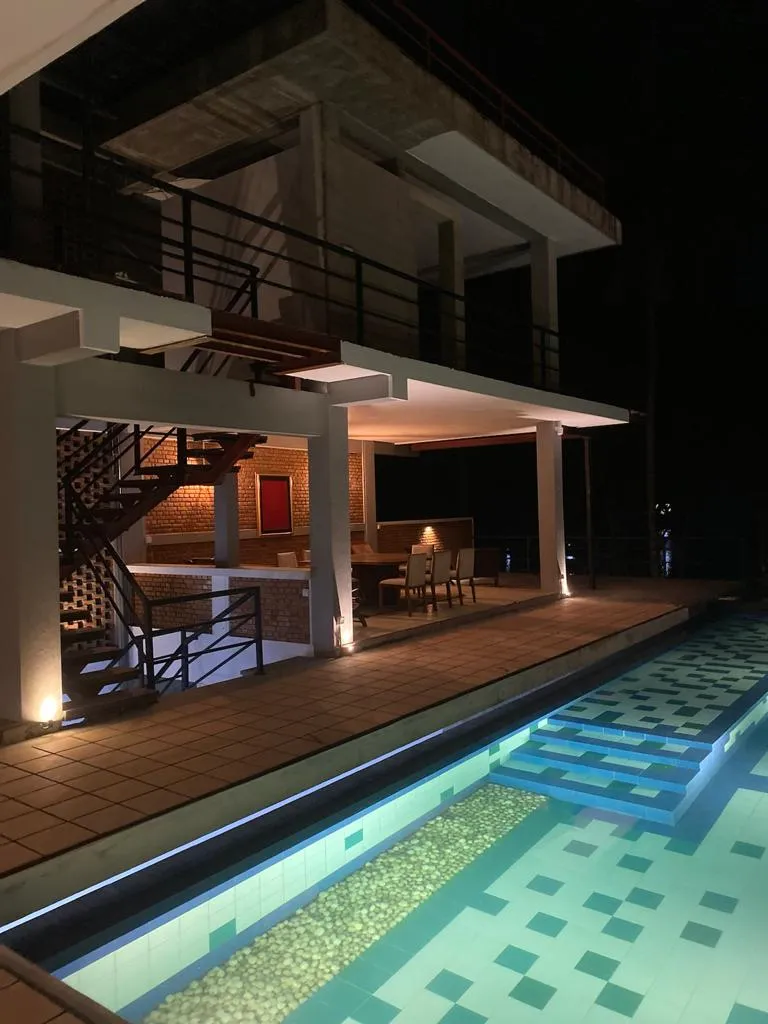 Illuminated pool and outdoor dining terrace at night at Ko Lake Villa